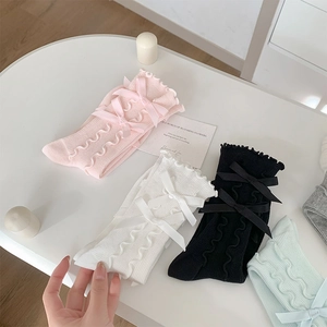 Detail of ruffled edges and double bow accents on ballet-style knit crew socks