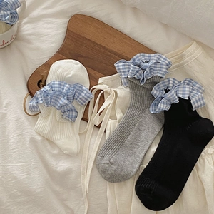 Detail of three mid-calf cotton socks in white, grey, and black with blue gingham lace edges