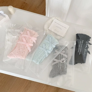 Detail of five colors of ruffled socks with bows in individual zipper bag packaging