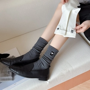 Detail of rib-knit mid-calf socks with heart embroidery and stylish letter patches