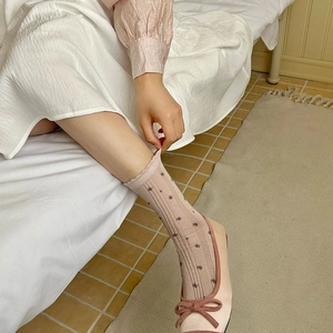 Détail de chaussettes en coton rose avec broderie florale et ballerines à nœuds