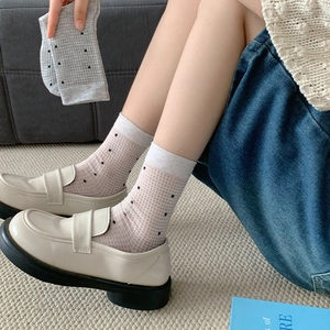 Close-up of breathable mesh polka dot socks paired with retro cream loafers