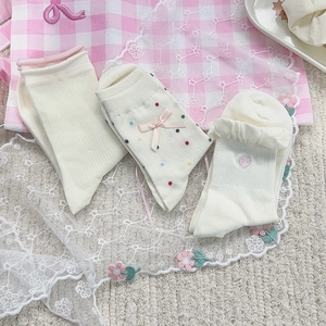 Dettaglio calzini in cotone beige con pois, fiocchi e ricami a cuore su bordo a volant