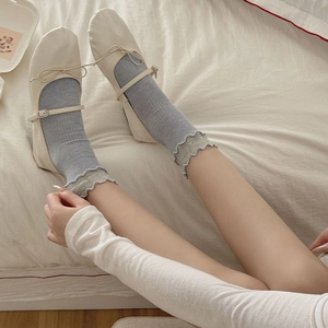 Détail de chaussettes bleu clair à bord volanté avec des ballerines Mary Jane crème