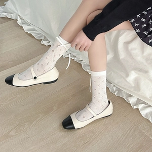 Detail of white hollow mesh socks with ribbon bows and Mary Jane shoes in retro style
