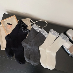 Detail view of sequined cuffs on ribbed crew socks in black, grey, and off-white colors