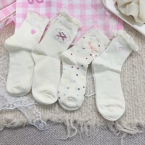 Dettaglio di calze in cotone bianco con volant, fiocchi rosa e ricami a forma di cuore