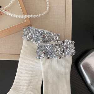 Detail of white ribbed socks with sparkling silver sequins and premium cotton knit texture