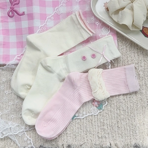 Dettaglio di tre paia di calzini in cotone a coste rosa e crema con fiocchi e pizzi