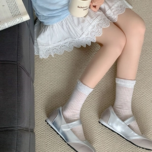 Vertical ribbed cotton mid-calf socks paired with silver metallic Mary Jane shoes on a rug