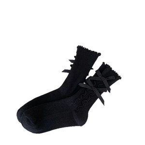 Black ballet style calf socks with ruffle trim and satin bows on a white background