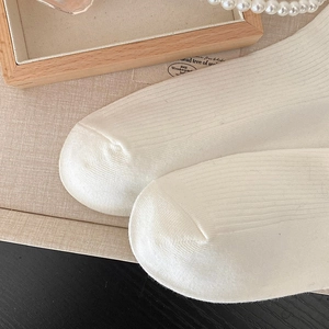 Detailed close-up of ribbed knit texture on ivory white socks with a cozy aesthetic