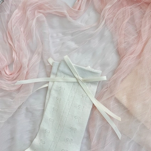 Close-up of white mesh socks with satin bow details and knit butterfly patterns