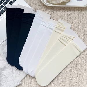 Lot de six paires de chaussettes à côtes en noir, blanc et crème sur un plaid en tricot