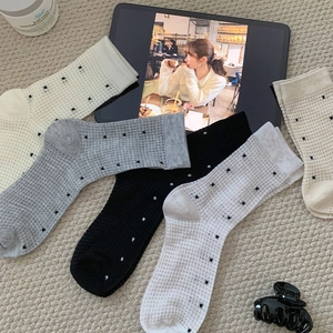 Close-up of three pairs of mesh polka dot socks in white, gray and black colors