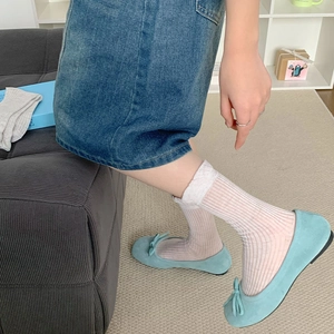 Close-up of light blue suede ballet flats with bow detail and white striped mid-calf socks