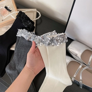 Detailed close-up of ribbed knit mid-calf socks featuring sparkling sequin embellishments