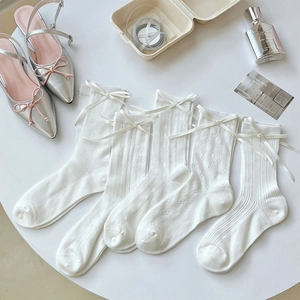 Close-up of five white mesh socks with satin bows and silver pointed ballet flats