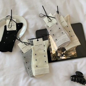 Detailed flatlay of breathable polka dot mid-calf socks in various earthy neutral colors