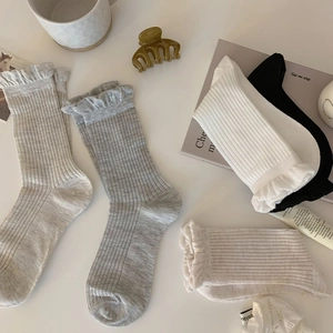 Detail of four pairs of ribbed knit socks with elegant ruffled cuffs in neutral colors
