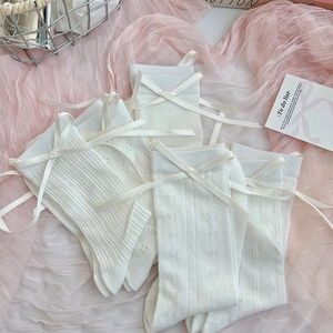 Detail view of cream white mesh socks with delicate silk bows and lace knit textures