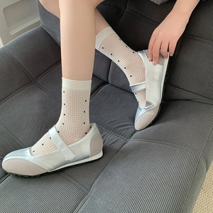 Close-up of silver Mary Jane shoes paired with white polka dot mesh socks on a model
