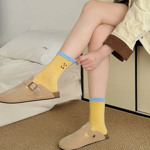 Detail of yellow cotton socks with blue trim and smile embroidery with mule shoes