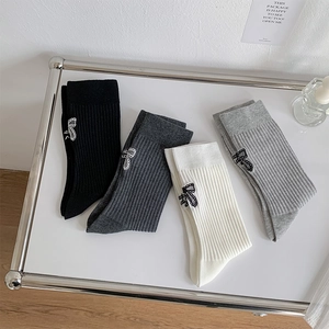 Detail of ballet style cotton socks featuring bow embroidery and ribbed knit texture