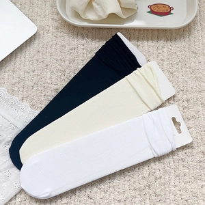 Détail de chaussettes en maille côtelée blanc, crème et noir sur un tapis beige
