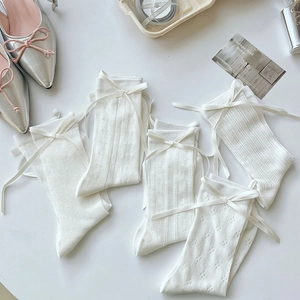 Close-up of white mesh socks with ribbon bows and assorted knit patterns in balletcore style