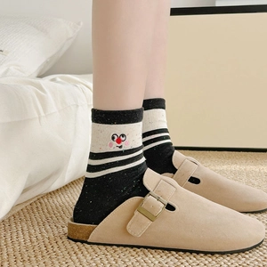 Detail of striped socks with smiley face embroidery and khaki suede mules with buckles