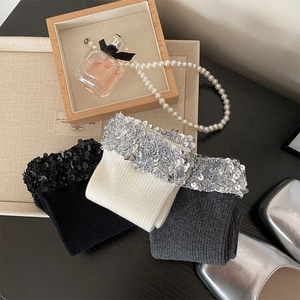 Detailed view of knitted socks with sparkly sequins in cream, grey, and black colors