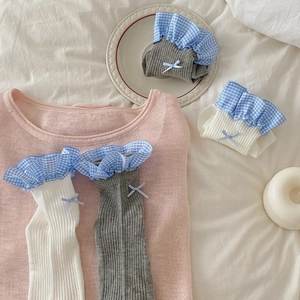 Dettaglio di pizzo a quadretti blu e fiocco su calzini da donna in maglia
