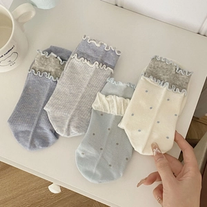 Détail de chaussettes en coton à bords volantés et motifs à pois aux tons pastels