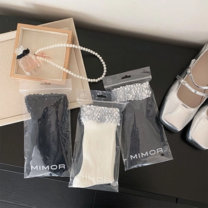 Detail view of stylish sequined mid-calf knit socks in black and white on a wooden desk
