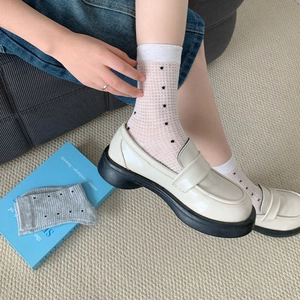 Close-up of white polka dot mesh socks paired with stylish off-white platform loafers