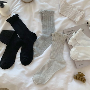 Detail of ruffled cuffs on ribbed cotton mid-calf socks in basic neutral colors