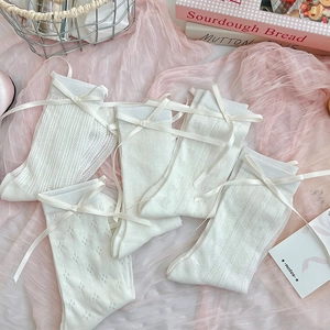 Detail showing five pairs of white mesh socks with bow accents and varied textures