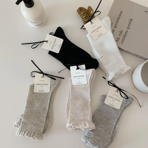 Detail of five pairs of ruffled edge crew socks in neutral tones with brand tags