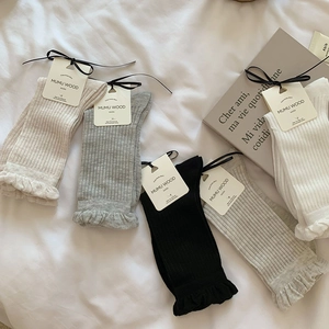 Detail of five pairs of ribbed mid-calf socks with ruffle cuffs and decorative paper tags