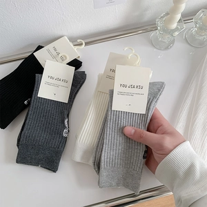 Detailed view of ballet-style ribbed crew socks with embroidery and brand hangtags