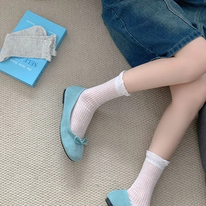 Detail of lake blue suede ballet flats with bow and white ruffled crew socks on grey rug