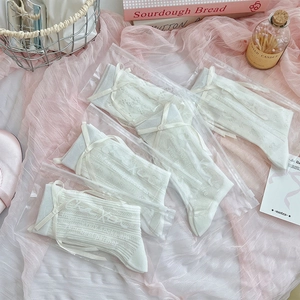 Close-up of four pairs of white lace socks with silk bows in zipper bag packaging