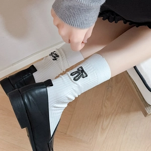 Detail of white cotton mid-calf socks with black bow and Sweet embroidery