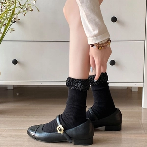 Detail of black mid-calf socks with sequins and Mary Jane shoes with flower buckles