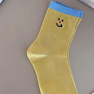 Detail of embroidered smiley face on ginger yellow cotton socks with blue cuffs