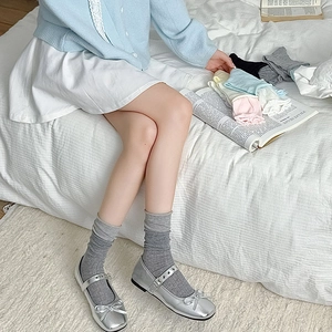 Gros plan de Mary Janes argentées avec chaussettes grises et options multicolores