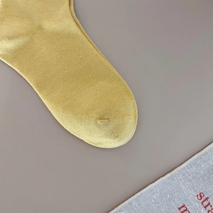 Close-up of ginger yellow knitted cotton sock toe showing fine needlework texture