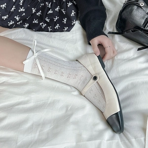Detail of white mesh crew socks with a ribbon bow paired with Mary Jane shoes
