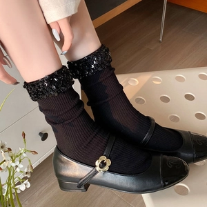 Detailed close-up of stylish black mid-calf socks with shiny sequined edge and leather shoes